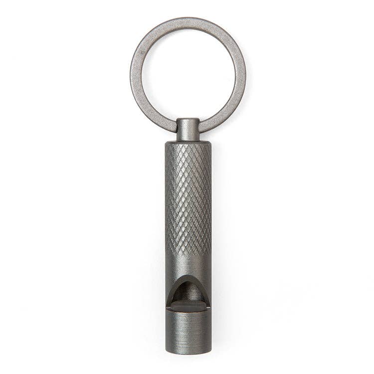 An emergency whistle with grip texture on a keyring over a flat white background