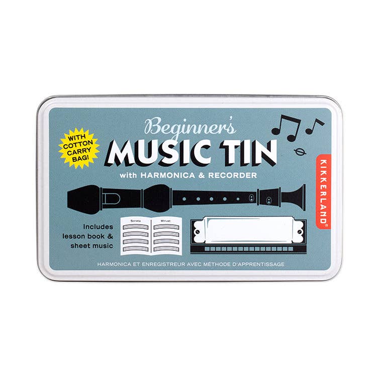 A Beginner's Music Tin kit by Kikkerlerand, shown in its rectangular metal tin packaging against a white background. The tin features a light blue-gray label with black and white graphics of a harmonica, a recorder, and a recorder book, along with a yellow burst that says 'with cotton carry bag'.