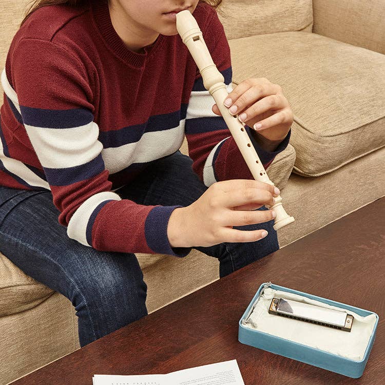 Person playing a recorder with a harmonica on a table